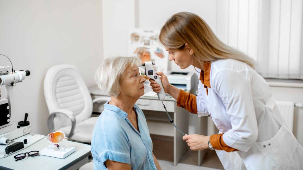 Geriatric optometrist in Tacoma performing an eye examination on an elderly patient using a handheld device
