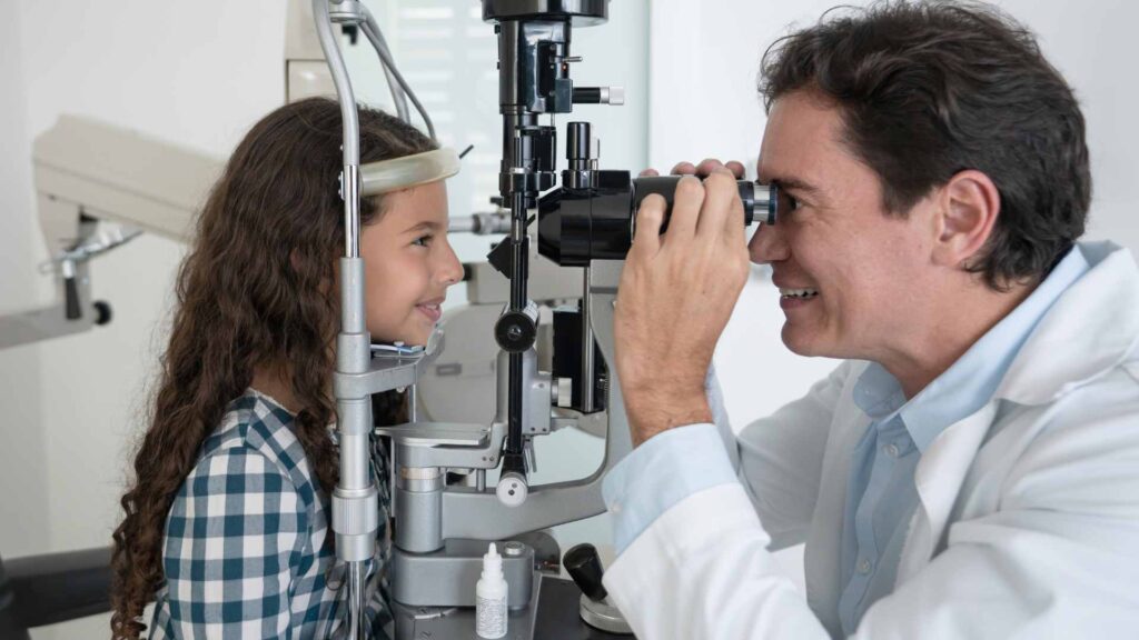 Smiling young girl receiving a pediatric eye exam from a friendly optometrist in Tacoma